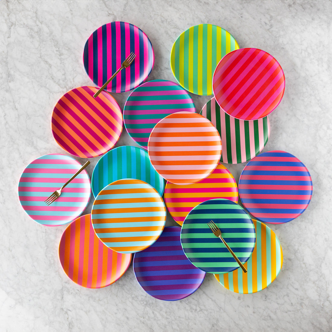 Colorful Stripe Melamine Plates are arranged on a marble surface, with three striped plates each holding a gold fork.