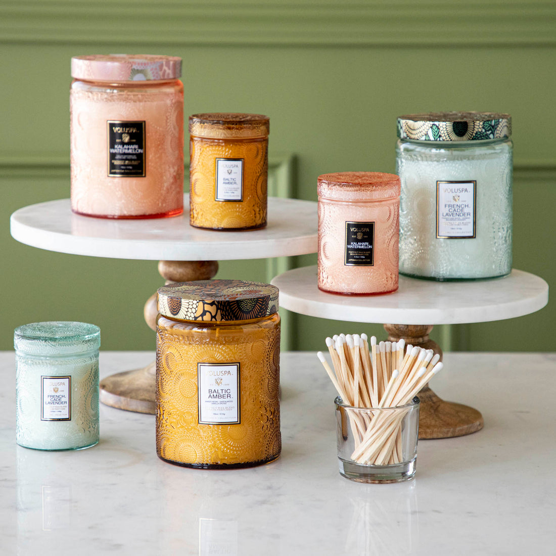 Two Voluspa French Cade Lavender candles on a marble surface with lemon verbena matchsticks.