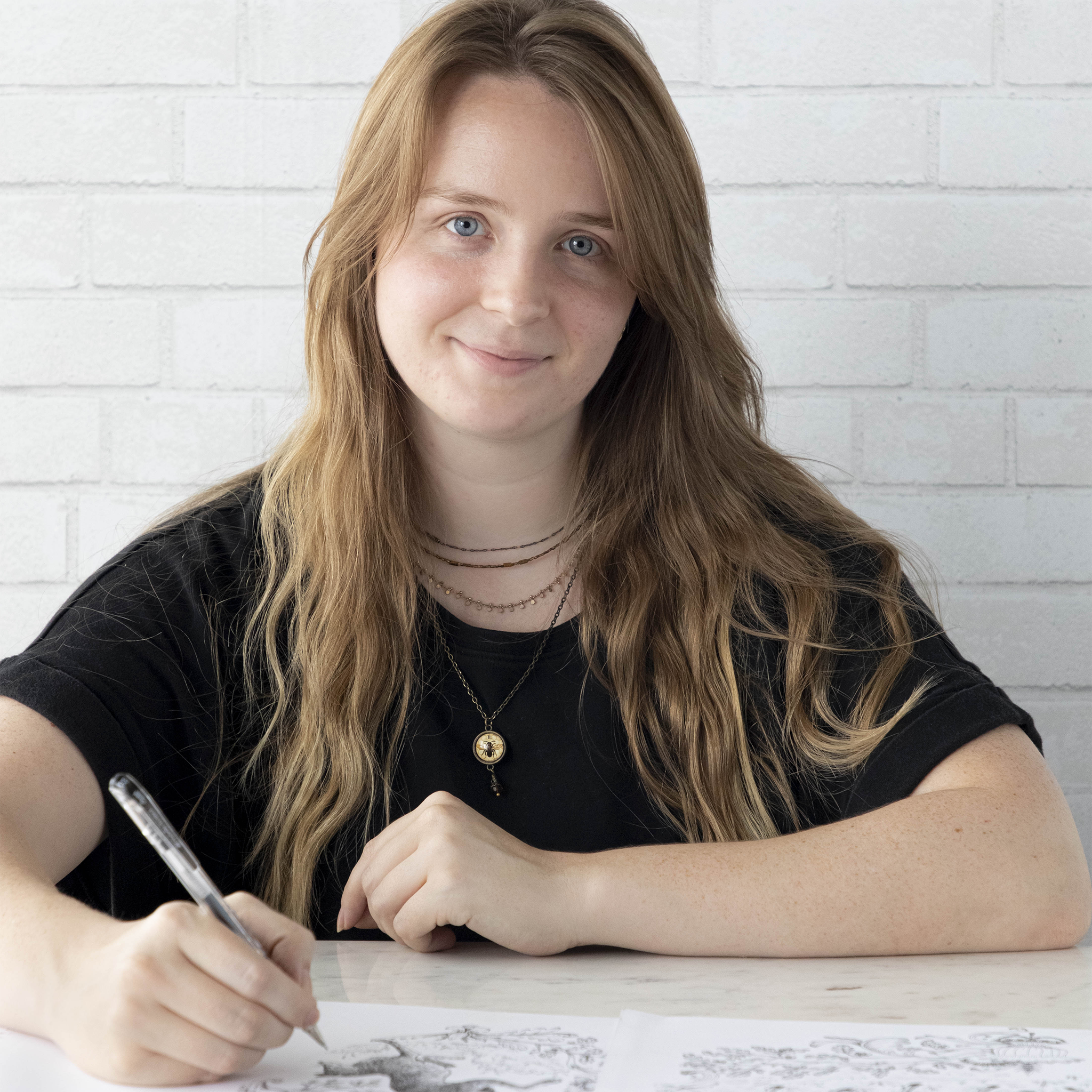 Caroline, an illustrator at Hester & Cook, smiling with a pen in her hand hovering over her illustration.