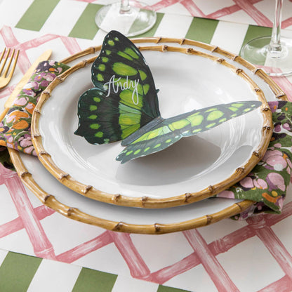 Butterfly Table Accent with &quot;Andy&quot; written in white ink on it, resting on bamboo dinner plates on an elegant place setting.