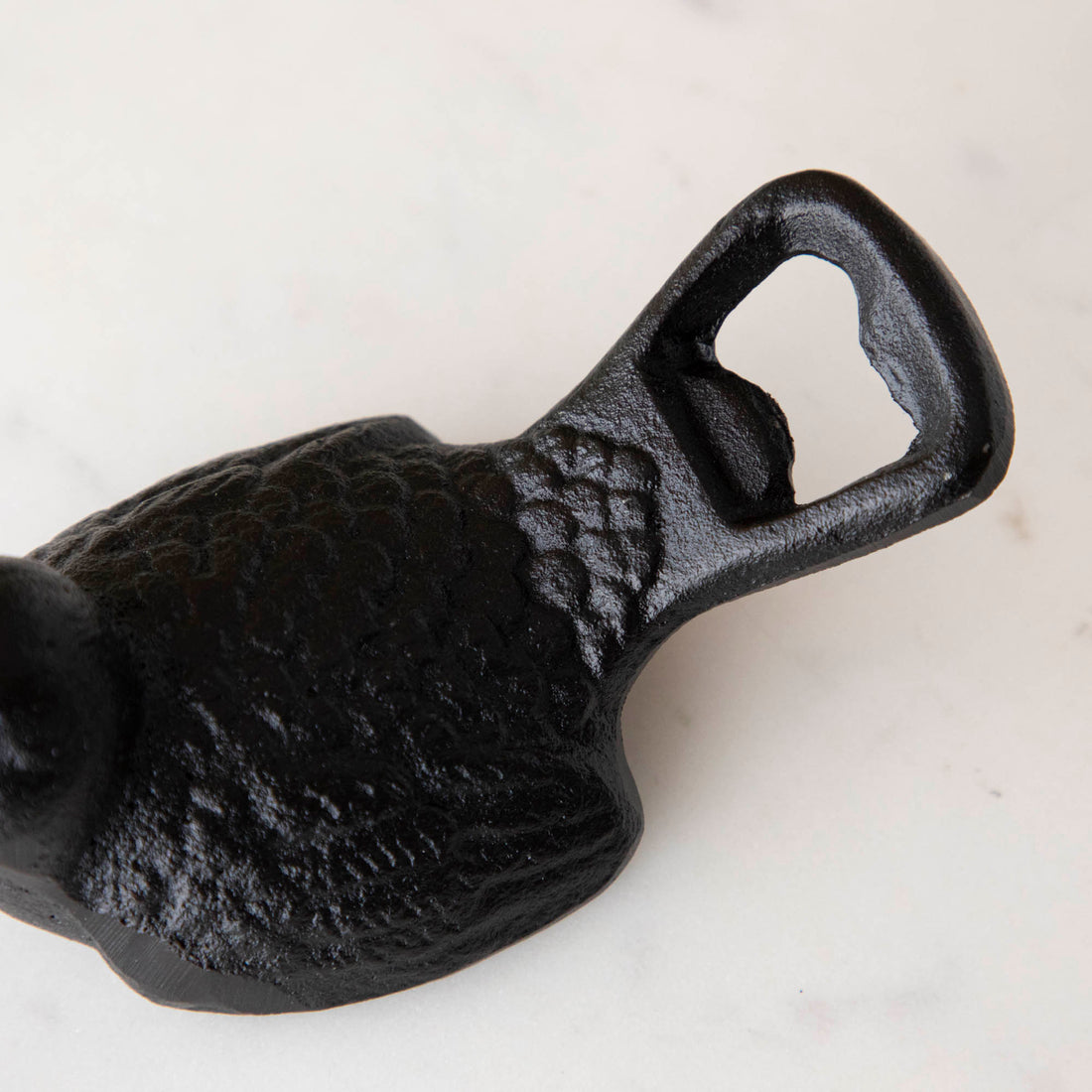 A small Park Hill Cast Iron Bird Bottle Opener with a rustic cast iron finish is sitting on a table.