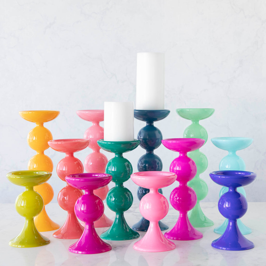A group of Glitterville Sweet Bubble Pillar Candle Holders in vibrant colors with a candle in the middle.