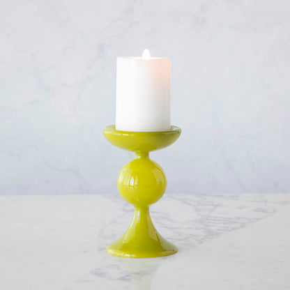 A group of Glitterville Sweet Bubble Pillar Candle Holders in vibrant colors with a candle in the middle.