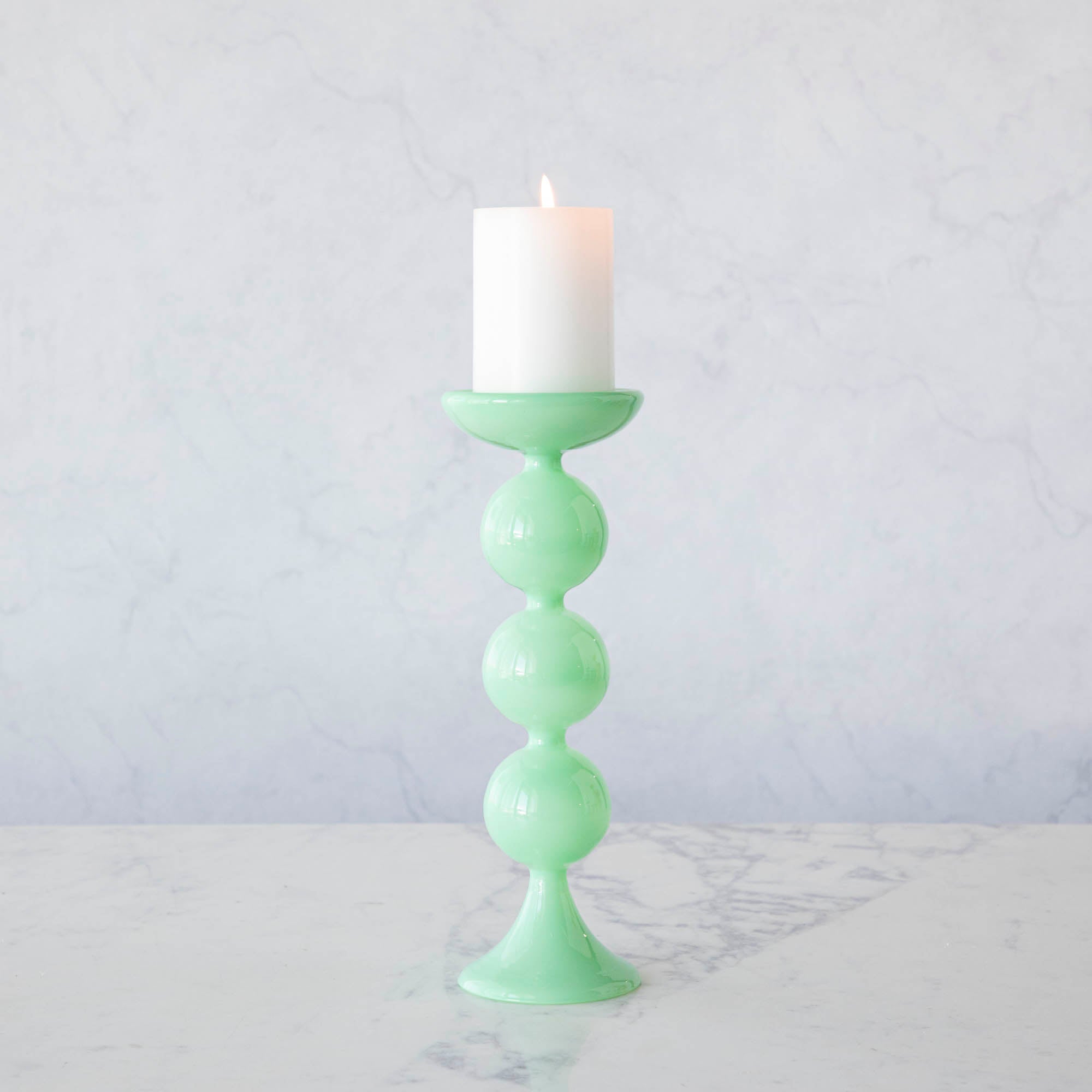 A group of Glitterville Sweet Bubble Pillar Candle Holders in vibrant colors with a candle in the middle.