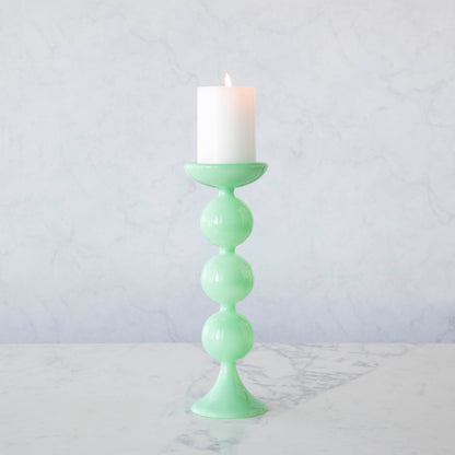 A group of Glitterville Sweet Bubble Pillar Candle Holders in vibrant colors with a candle in the middle.