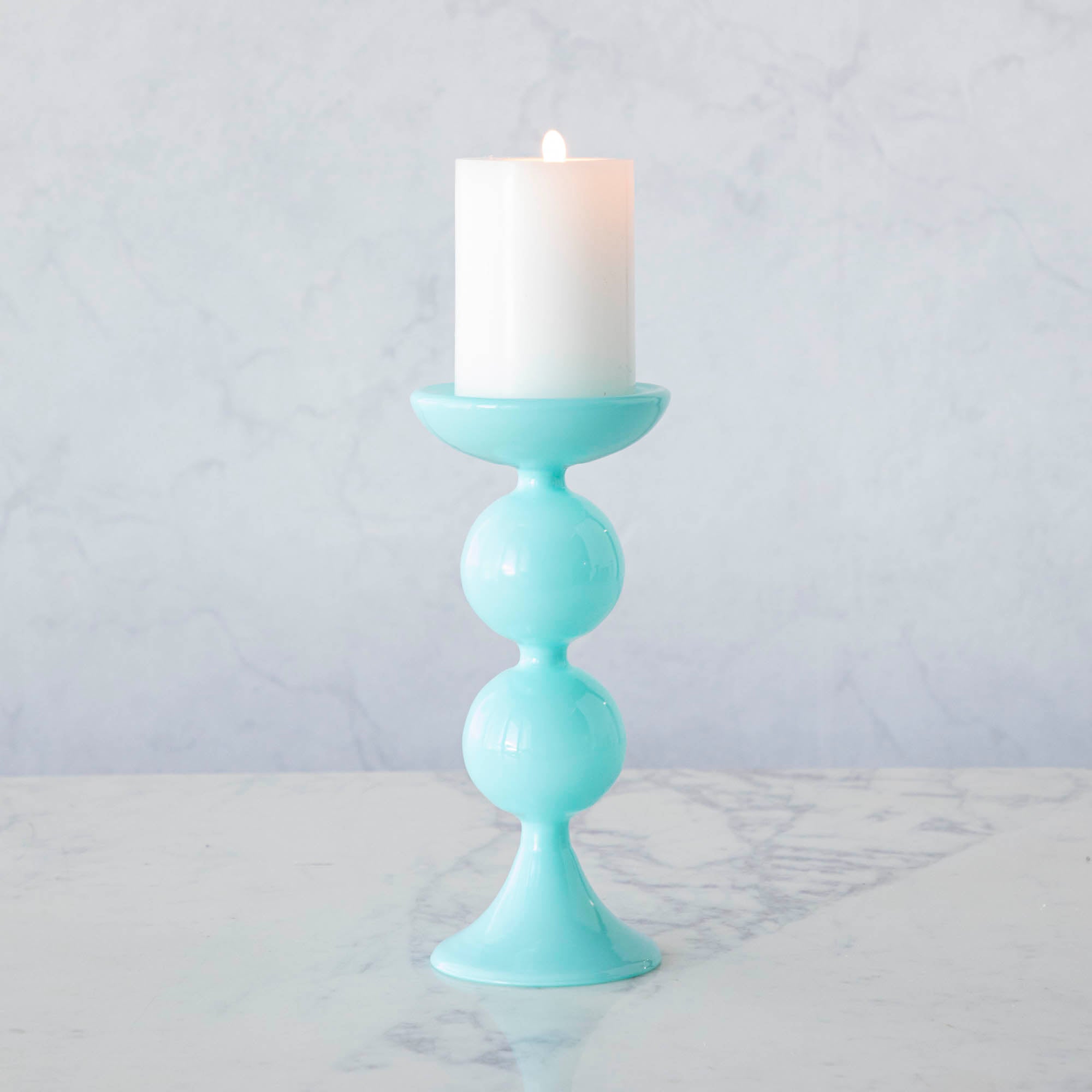 A group of Glitterville Sweet Bubble Pillar Candle Holders in vibrant colors with a candle in the middle.