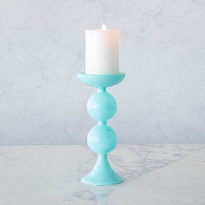 A group of Glitterville Sweet Bubble Pillar Candle Holders in vibrant colors with a candle in the middle.
