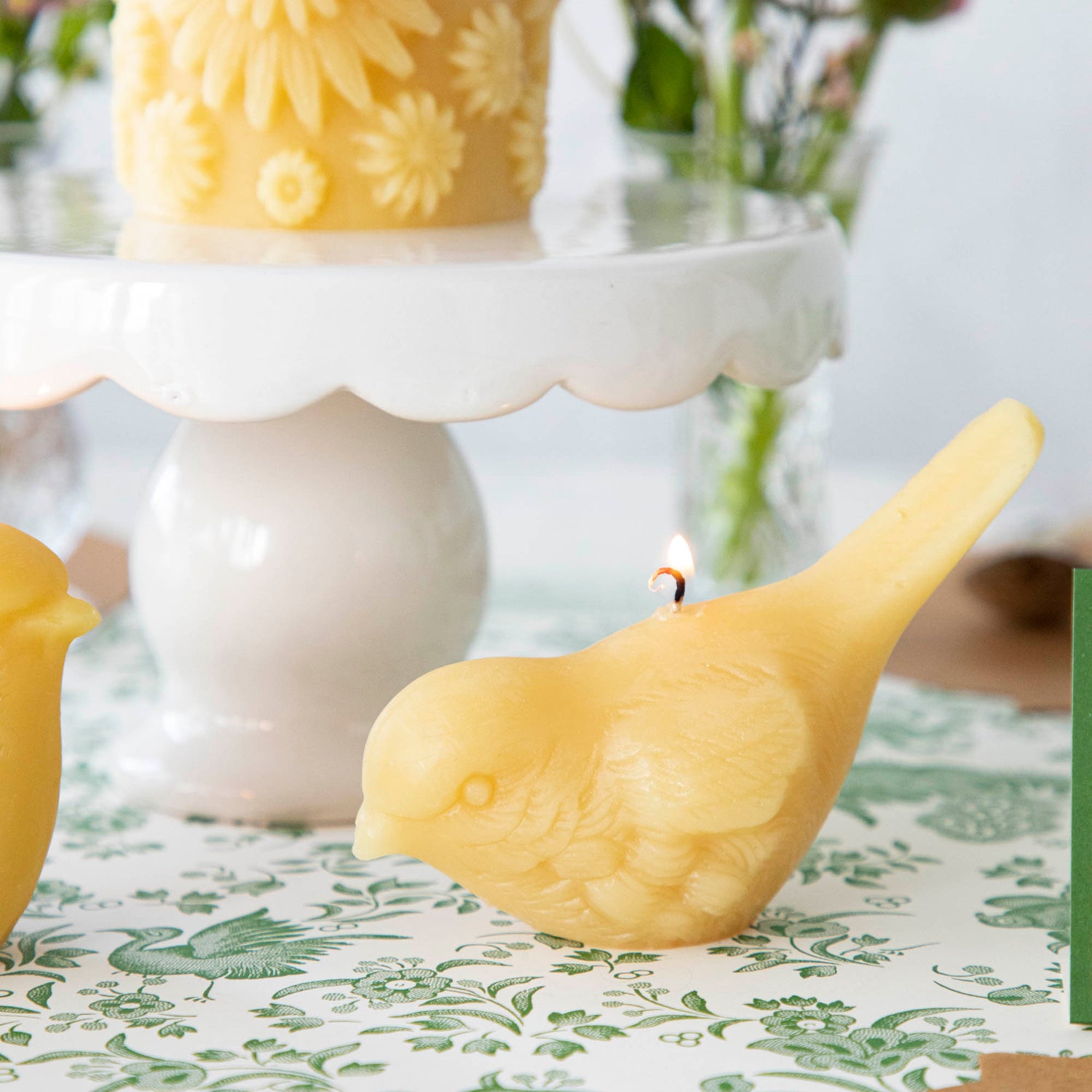 Two hand-casted Beeswax Songbirds Candles adorned with birds by Big Dipper Wax Works.