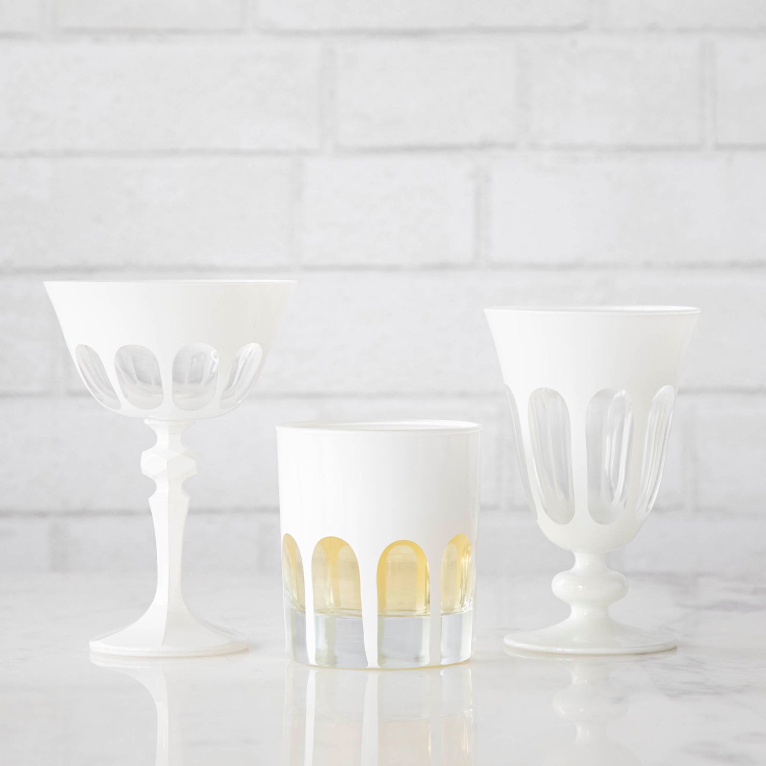 Three Rialto Chalk (White) Glasses by SIR/MADAM on a Venice-styled white brick wall.