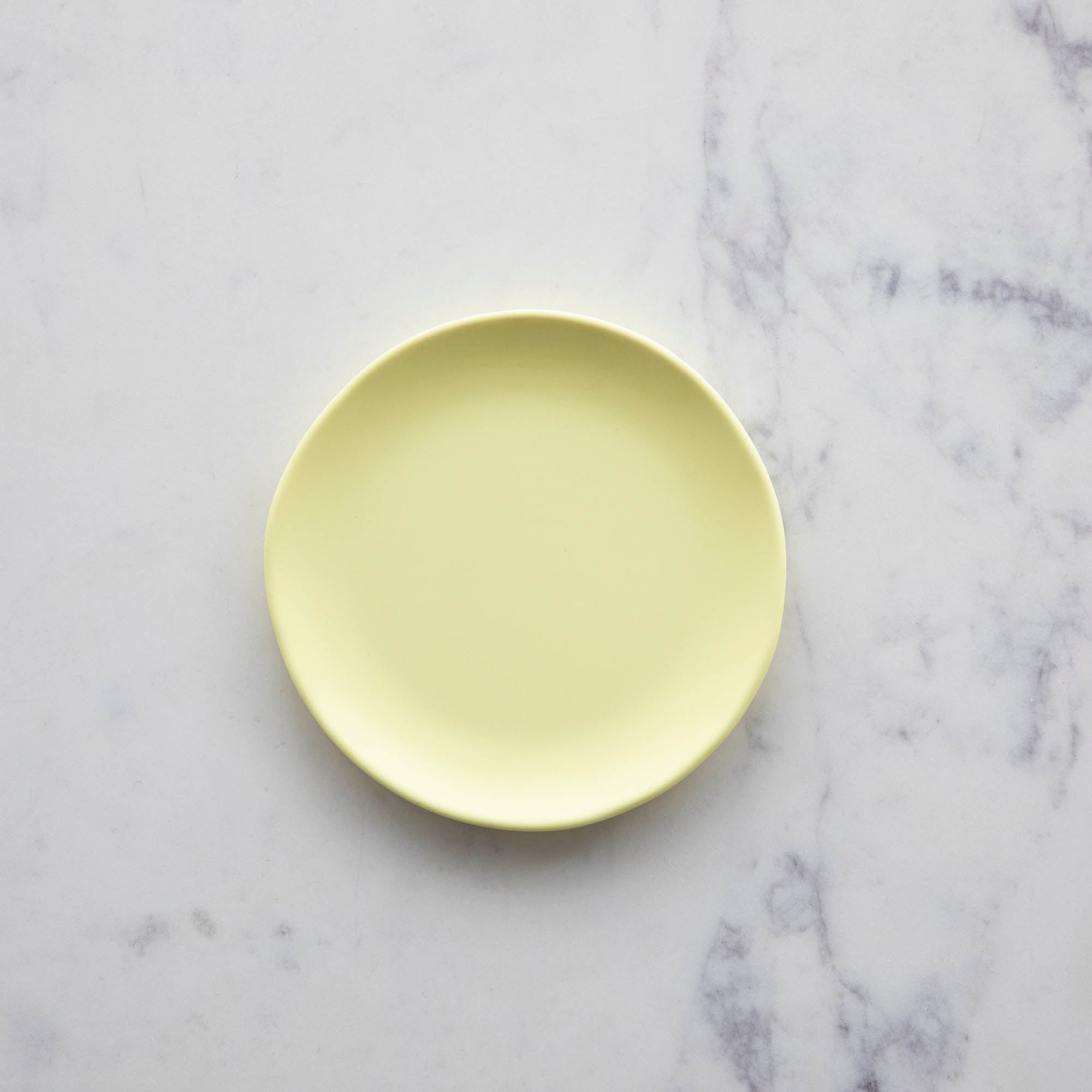 A 6&quot;  Buttercream Rainbow Melamine Plate by Glitterville on a marble surface.