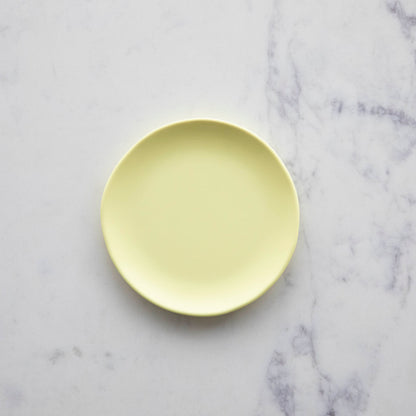 A 6&quot;  Buttercream Rainbow Melamine Plate by Glitterville on a marble surface.