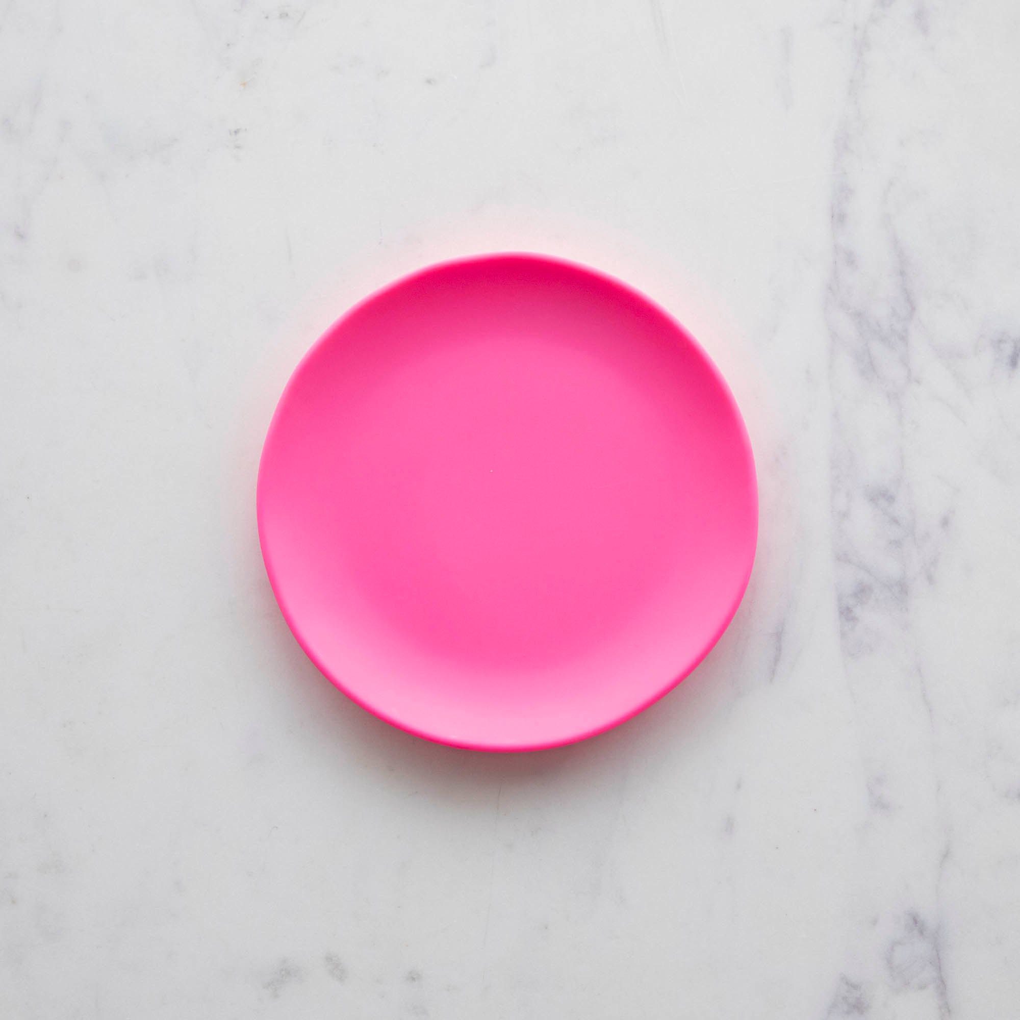 A 6&quot; melon Rainbow Melamine Plate on a marble surface from Glitterville.