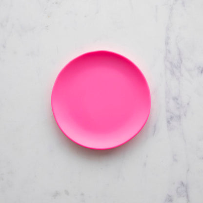 A 6&quot; melon Rainbow Melamine Plate on a marble surface from Glitterville.