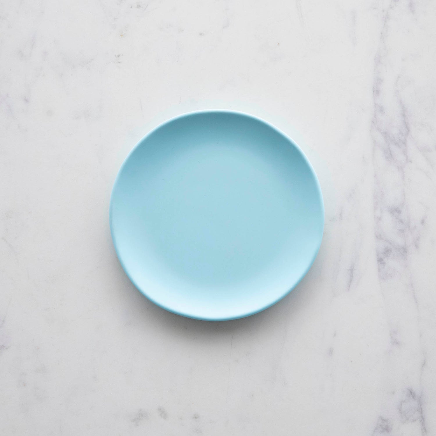 A 6&quot; Rainbow Melamine Plate by Glitterville on a marble surface.