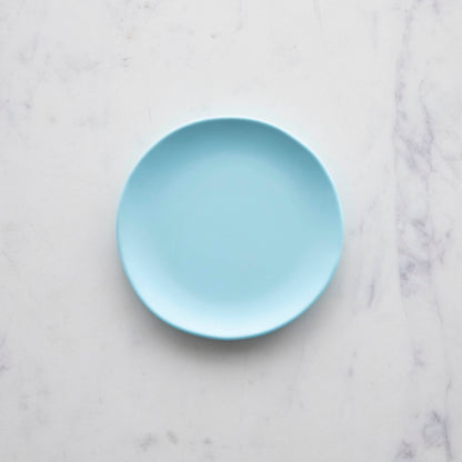 A 6&quot; Rainbow Melamine Plate by Glitterville on a marble surface.