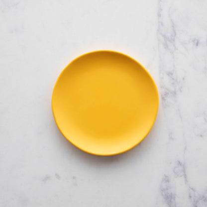 A Glitterville 6&quot; Rainbow Melamine Plate on a marble surface.
