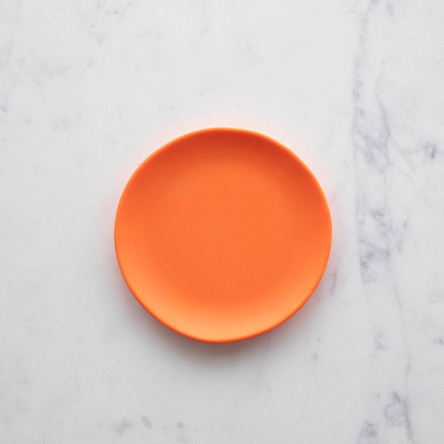 A 6&quot; Rainbow Melamine Plate by Glitterville on a marble surface.