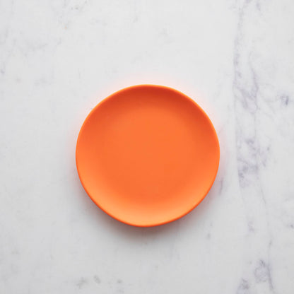 A 6&quot; Rainbow Melamine Plate by Glitterville on a marble surface.