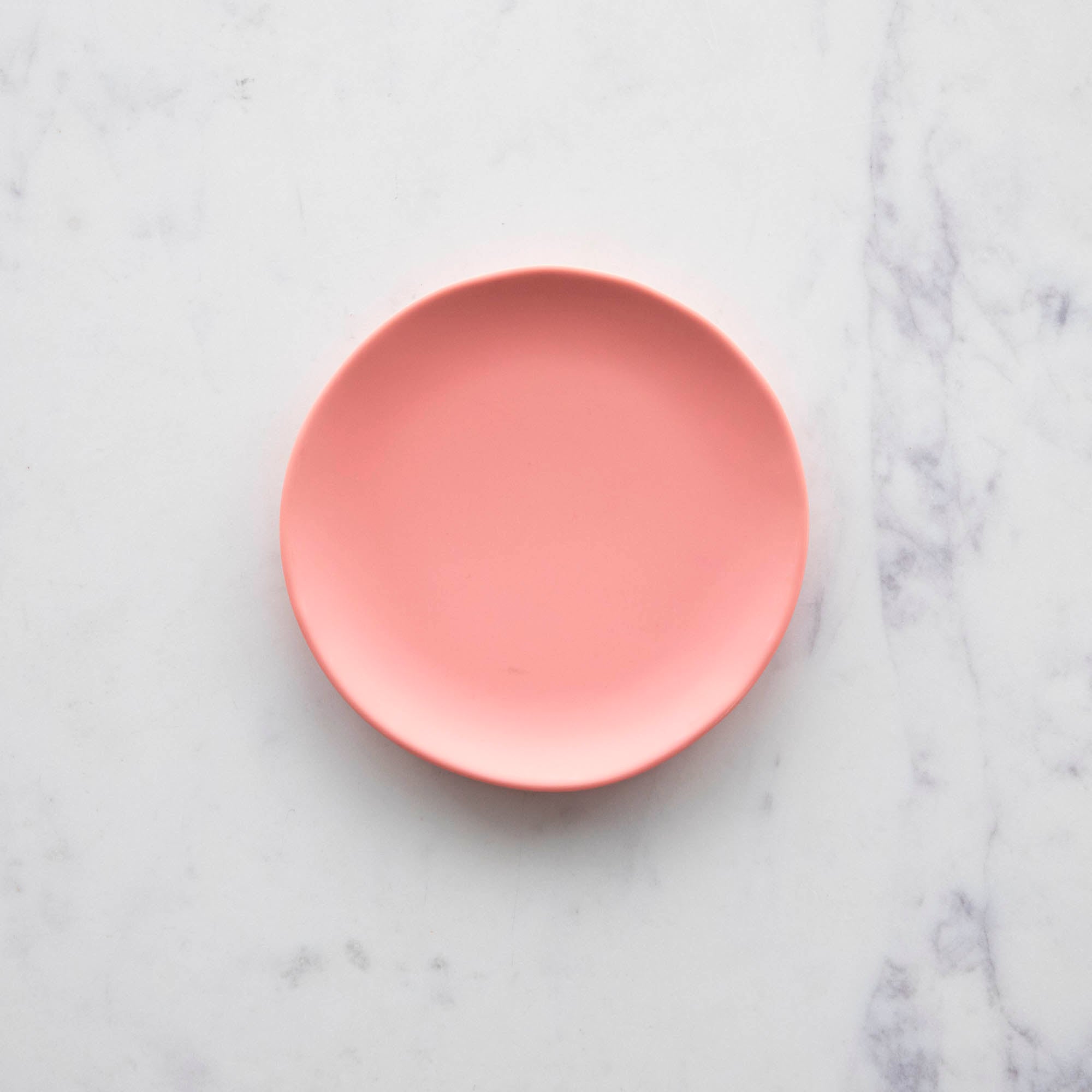 A colorful 6&quot; Rainbow Melamine Plate by Glitterville on a marble surface.