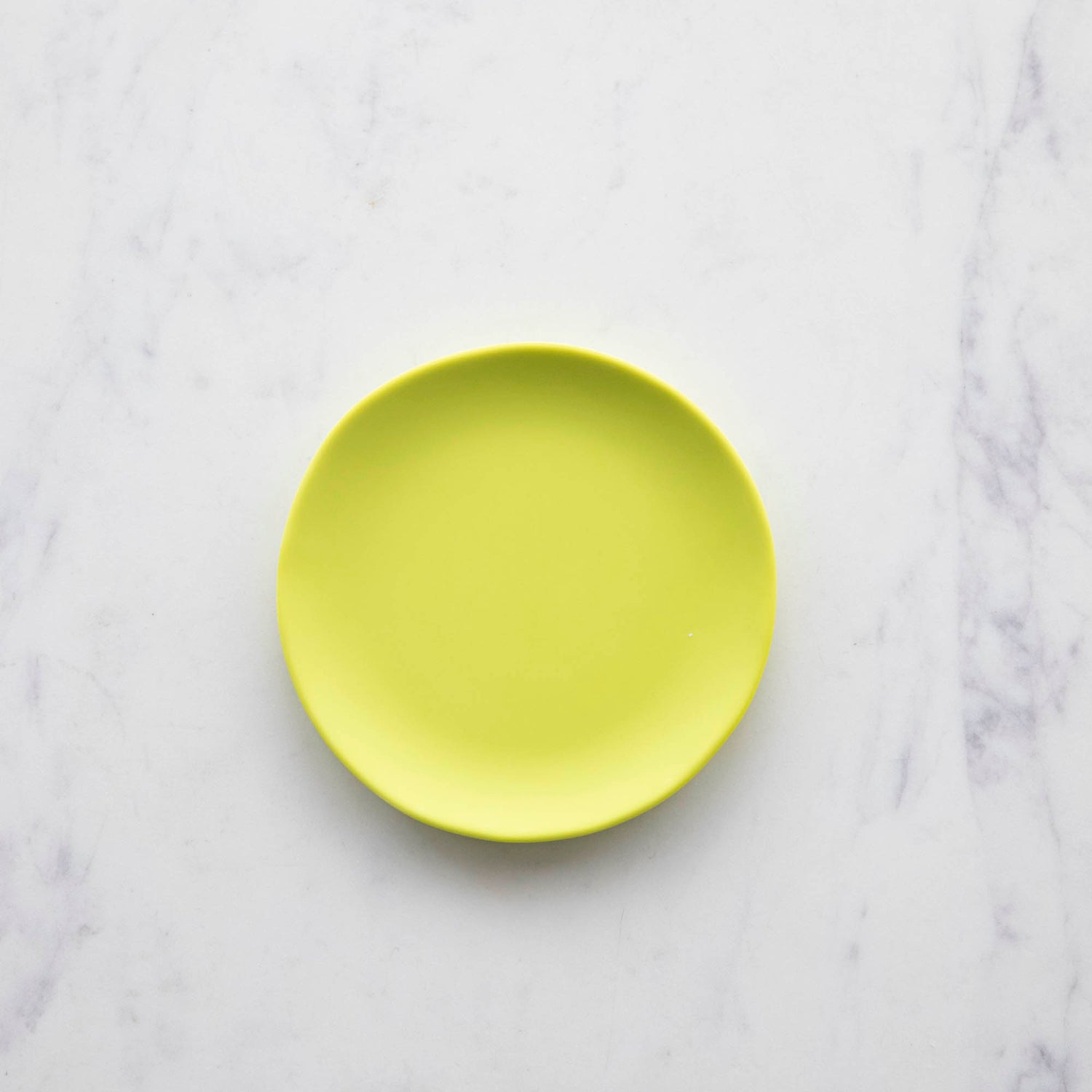 A colorful Glitterville Rainbow Melamine Plate on a marble surface.