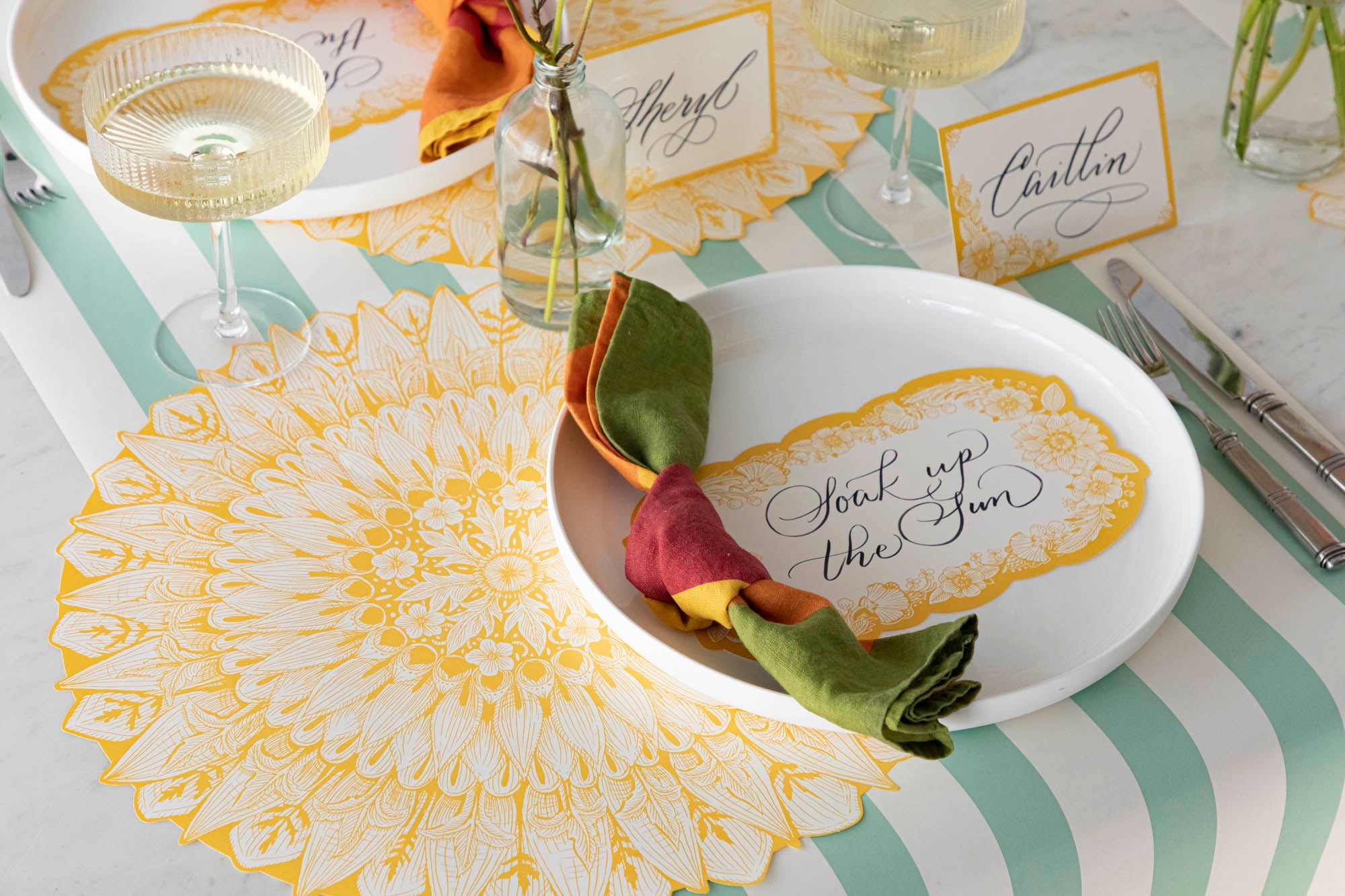 A Spring Blooms Table Card with &quot;Soak up the sun&quot; written on it in lovely script resting on the plate of a vibrant place setting.