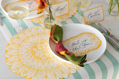 A Spring Blooms Table Card with &quot;Soak up the sun&quot; written on it in lovely script resting on the plate of a vibrant place setting.