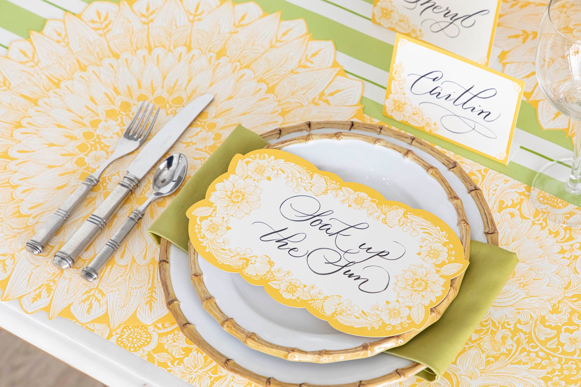 Close-up of a Spring Blooms Table Card with &quot;Soak up the sun&quot; written on it in lovely script resting on the plate of a vibrant place setting.