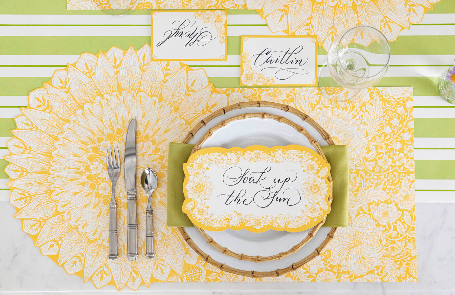 A Spring Blooms Table Card with &quot;Soak up the sun&quot; written on it in lovely script resting on the plate of a vibrant place setting.