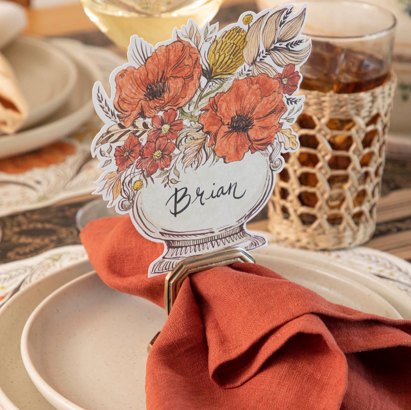 A close up view of the Autumn Arrangement Place Card with the name &quot;Brian&quot; written on it, on a fall themed table setting.