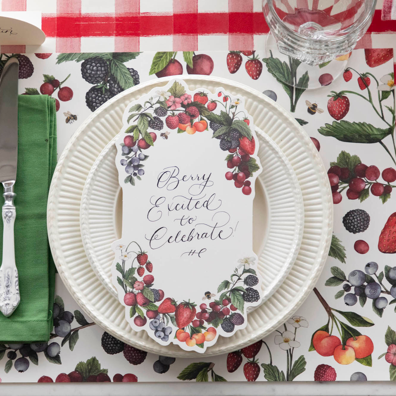 Top-down view of a berry-themed place setting featuring a Berry Bramble Table Card with &quot;Berry Excited to Celebrate&quot; written on it in lovely script.