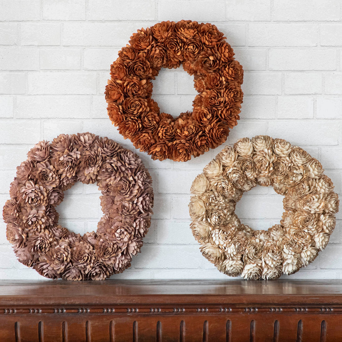 3 Shola Almond Flower Wreaths shown on a mantle with greenery