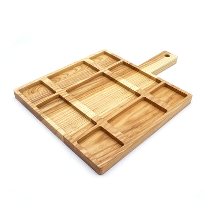 A JK Adams Ash Divided Serving Board with compartments holding pistachios, blueberries, crackers, and a dip, next to a small vase with greenery.