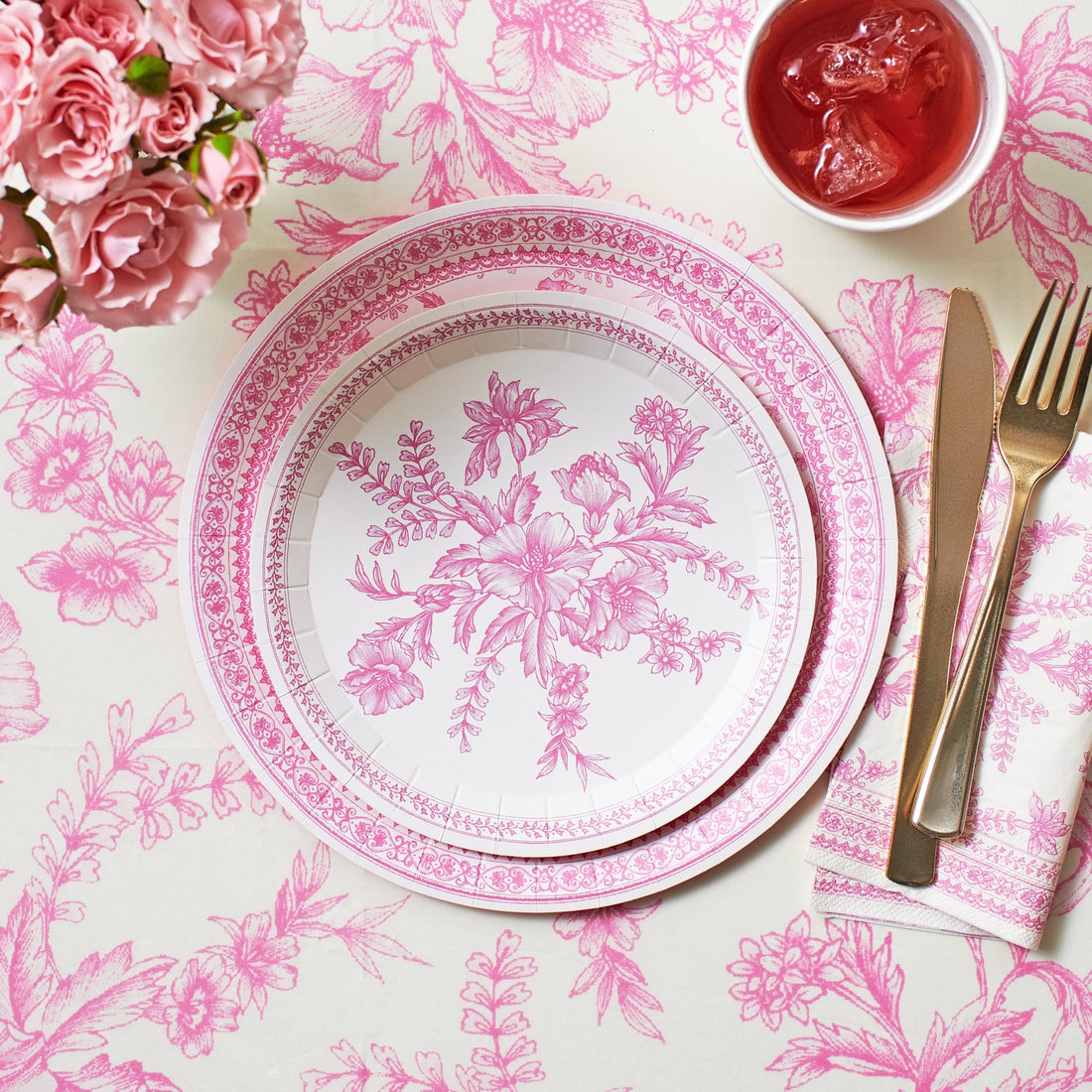 Pink French Toile Paper Tablecloth on a table with coordinating plates. 