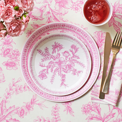 Pink French Toile Paper Tablecloth on a table with coordinating plates. 