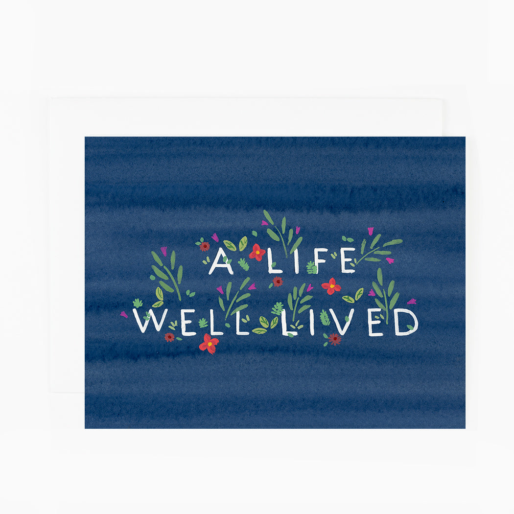 A blue greeting card with flowers surrounding text that reads &quot;A life well lived&quot;