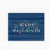 A blue greeting card with flowers surrounding text that reads "A life well lived"