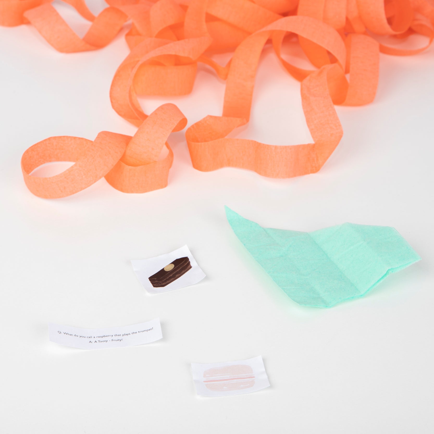 A piece of Meri Meri tissue paper and a piece of white paper with Ladurée Paris Macaron Surprise Balls on a white surface.