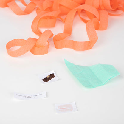 A piece of Meri Meri tissue paper and a piece of white paper with Ladurée Paris Macaron Surprise Balls on a white surface.