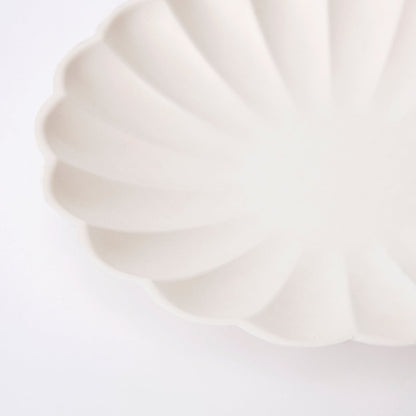 A Meri Meri cream eco plate with a scalloped edge.