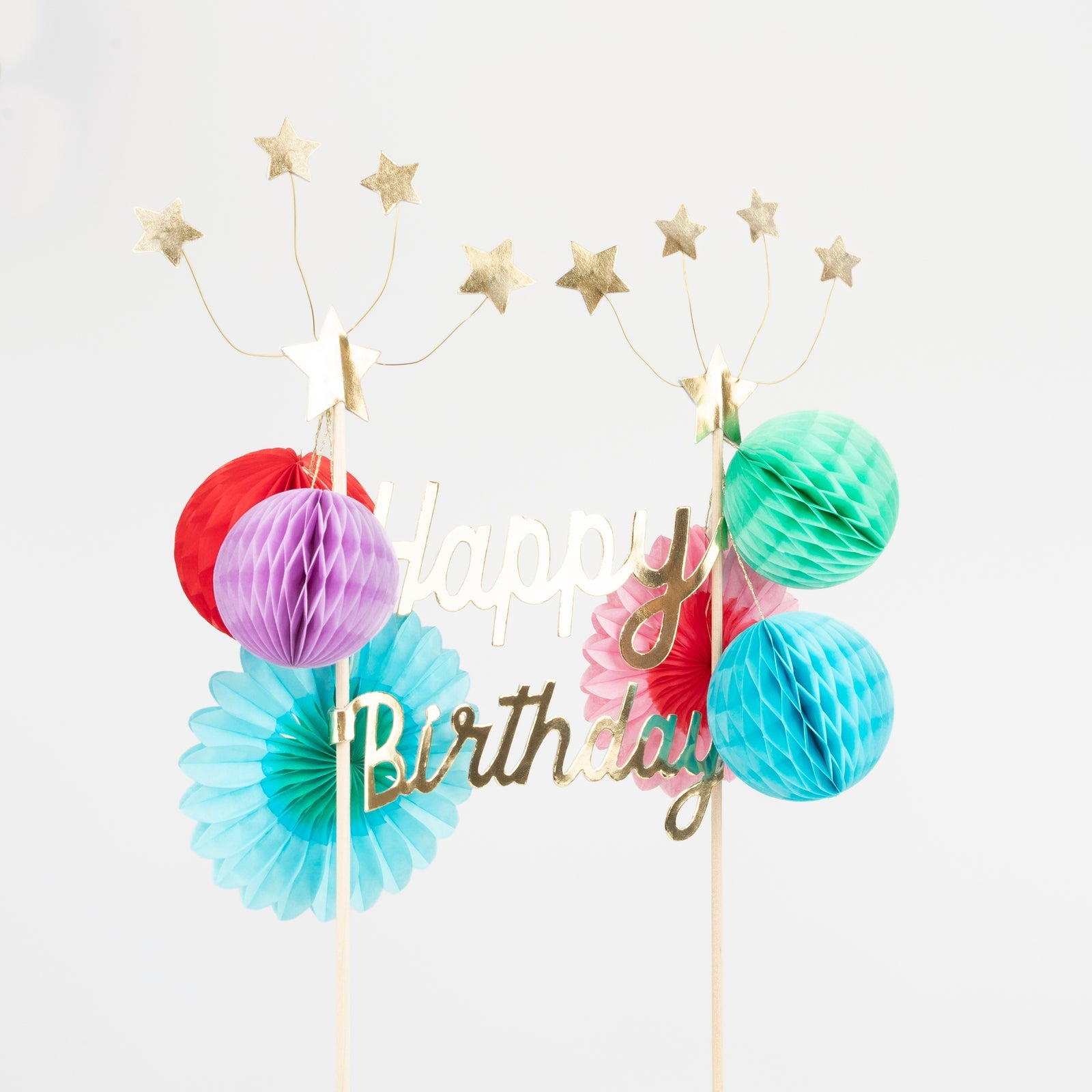 A Happy Birthday Honeycomb Cake Topper with gold foil stars and pom poms by Meri Meri.