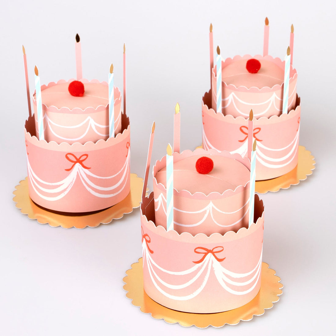 3D Paper hats in the shape of a cake with candles and red felt pom poms.