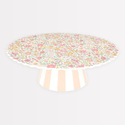 Meri Meri x Liberty Reusable Cake Stand with Liberty floral print in pinks, yellows and oranges on top and a pink and white striped base. 