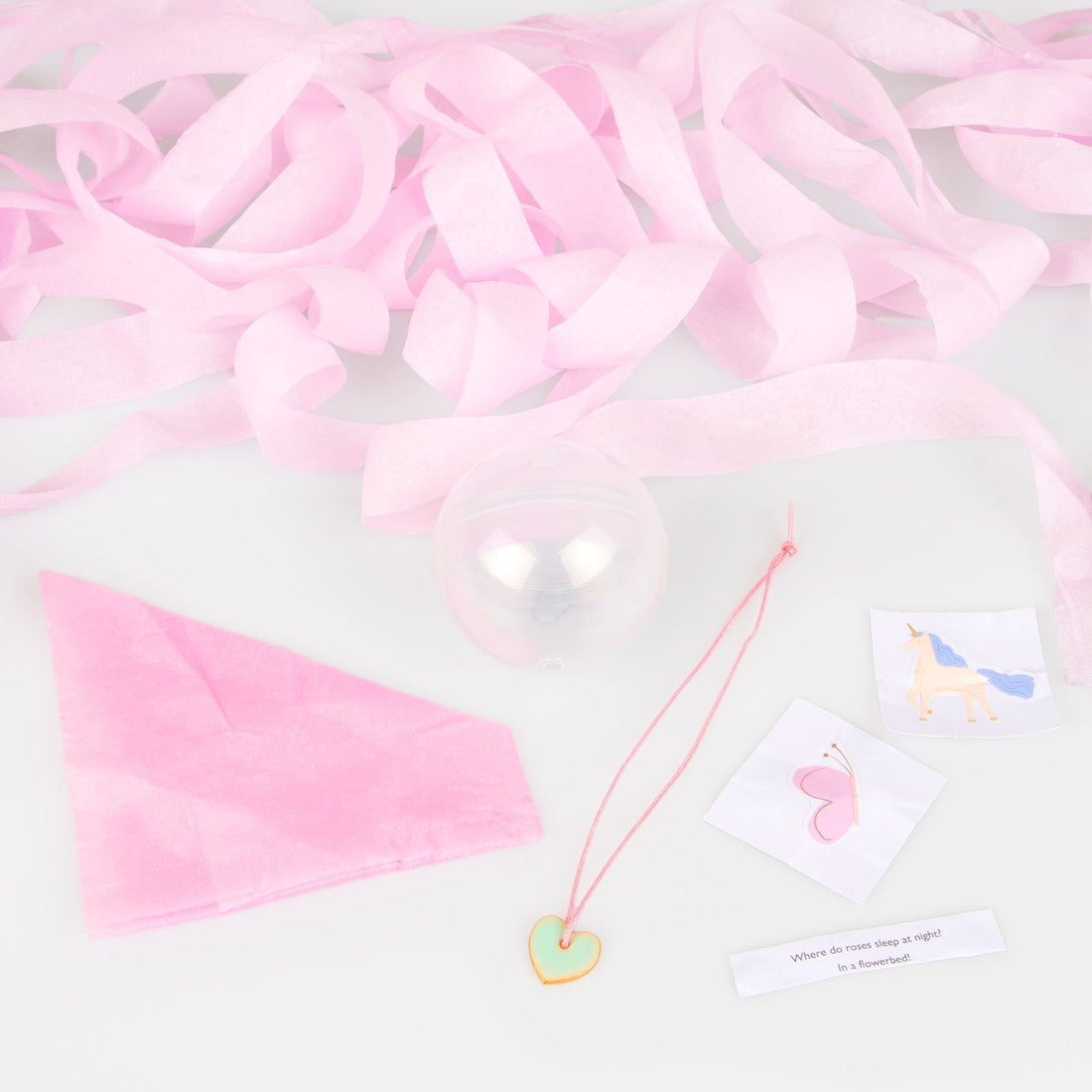 A pink tissue paper party hat, 2 stickers, a joke and a heart enamel charm. 