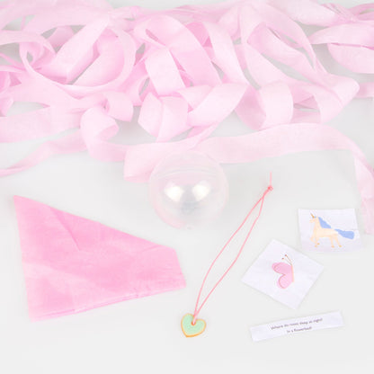 A pink tissue paper party hat, 2 stickers, a joke and a heart enamel charm. 