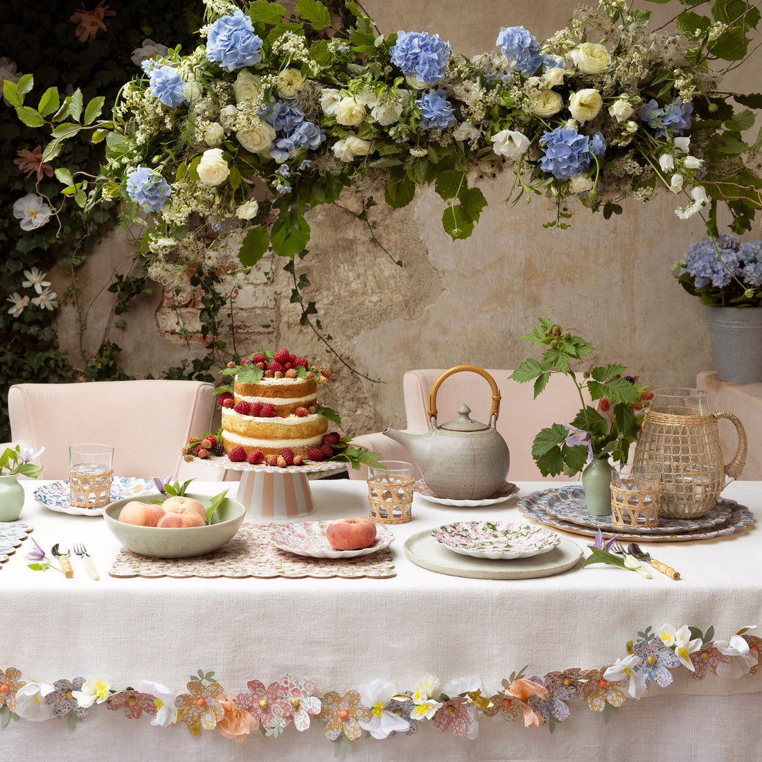 Set table with a cake and teapot and various Meri Meri x Liberty plates and cakes stands on it. 