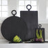 A set of three Be Home Blackened Serving Boards of different shapes and sizes with fresh vegetables displayed in front of a window.