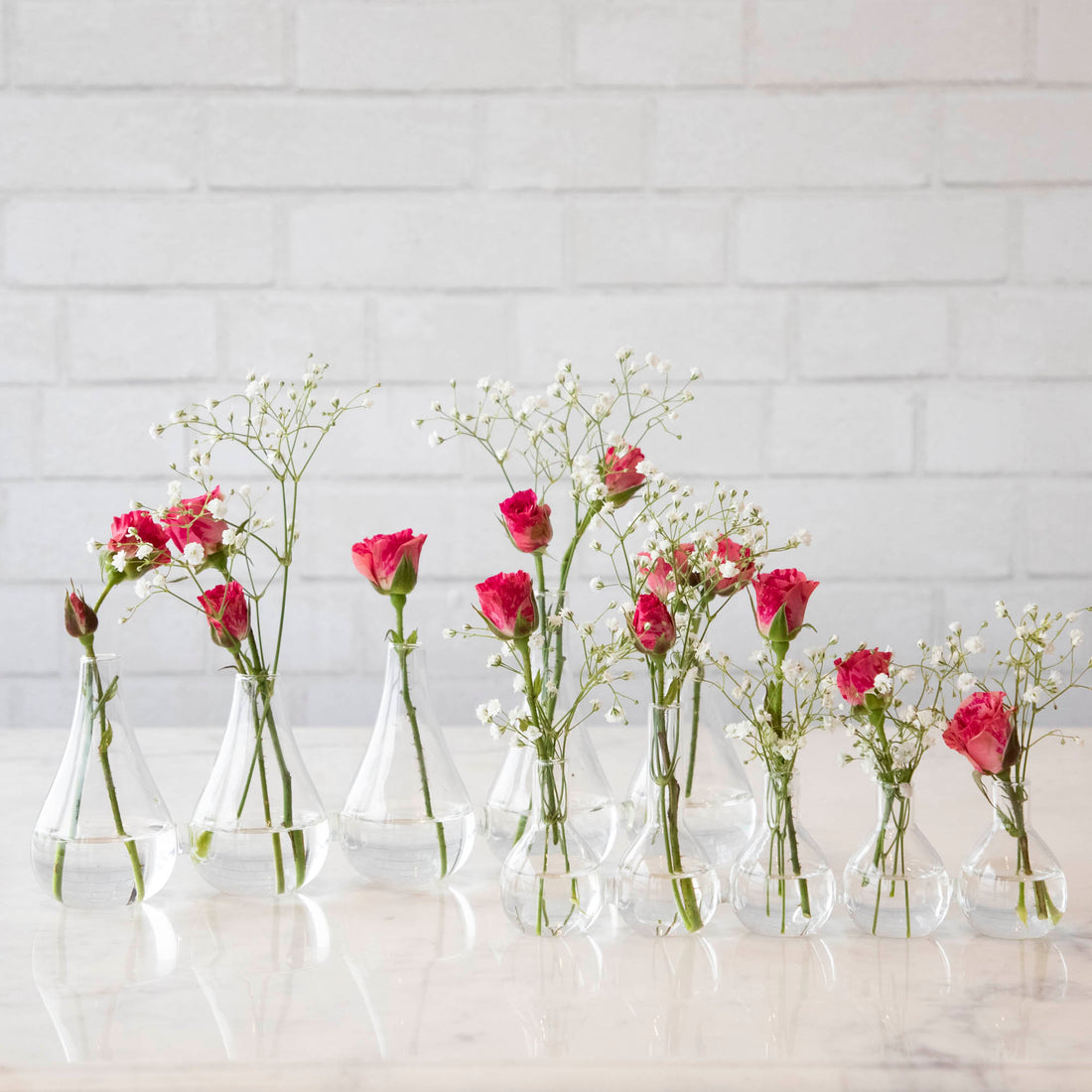 Five Quintet Glass Vases of varying shapes holding floral cuttings of pink roses and baby&