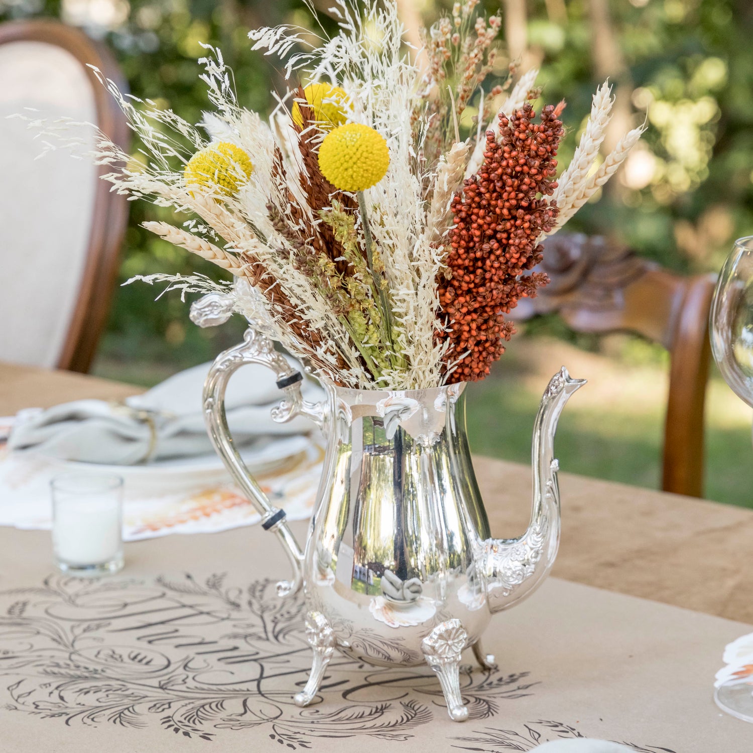 A blue and white table setting with a vase of tulips and Hester &amp; Cook vintage silver-plated tea servers.