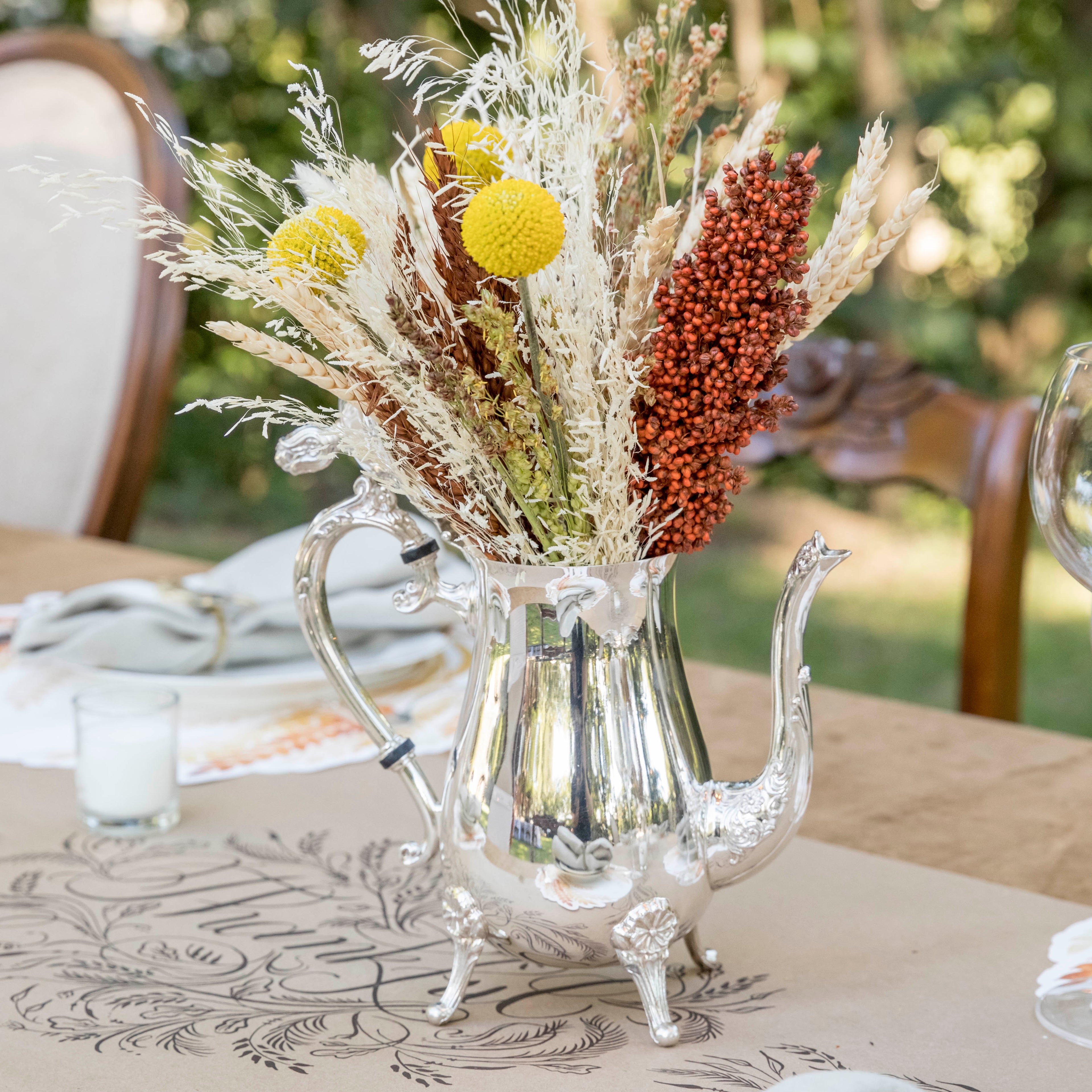 A blue and white table setting with a vase of tulips and Hester &amp; Cook vintage silver-plated tea servers.