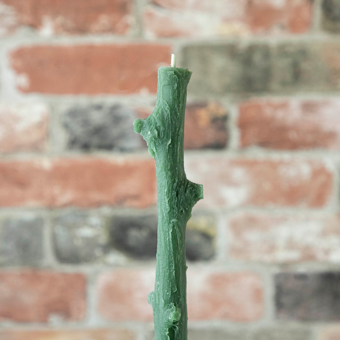 A Stick Candles set and a group of candles on top of a textured brick wall.